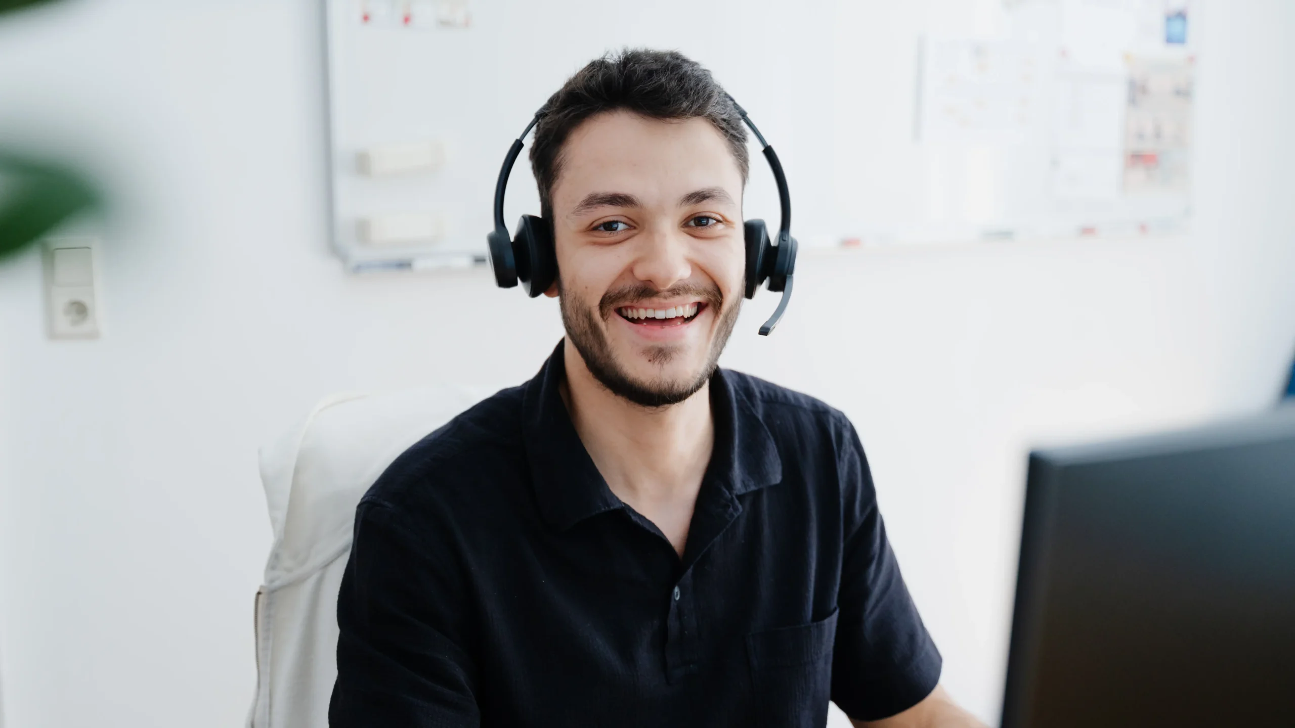 Freundlich lächelnder Mitarbeiter mit Headset, der für Kundengespräche bereitsteht