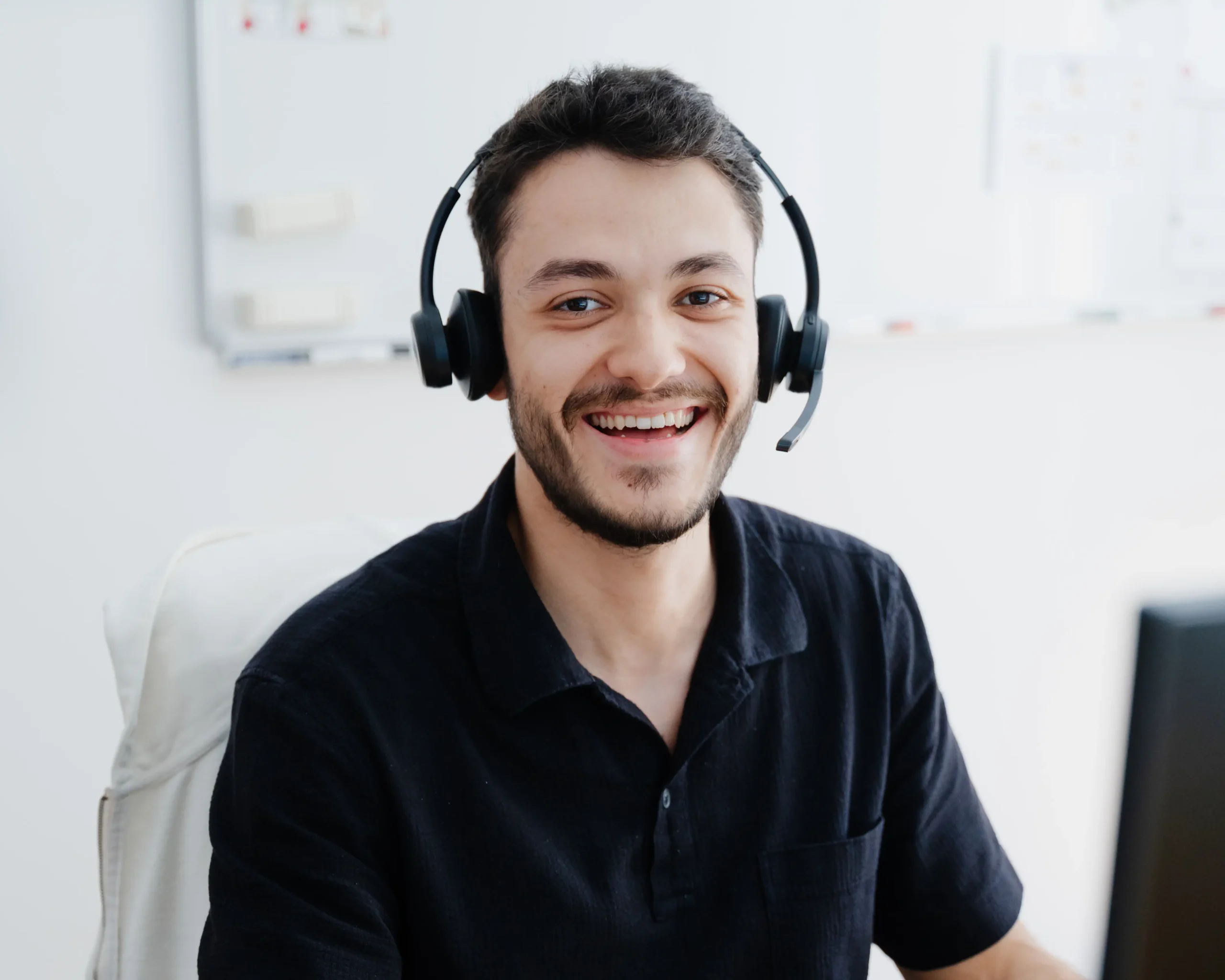 Freundlich lächelnder Mitarbeiter mit Headset, der für Kundengespräche bereitsteht